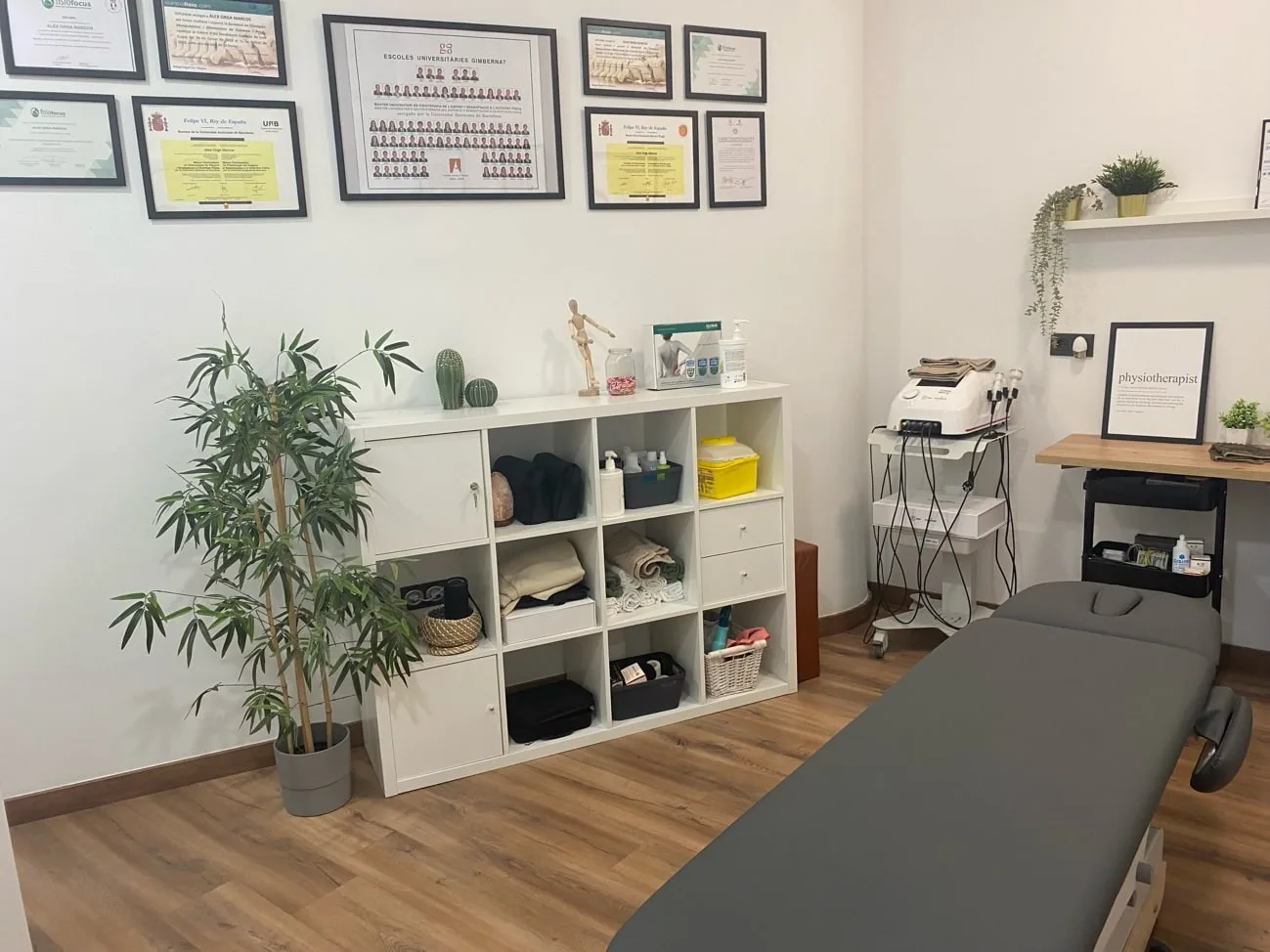 Consulta de fisioteràpia de Physeo Clinic amb la llitera i les titulacions de l'equip